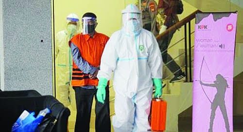 KAWAL—Seorang petugas dinas kesehatan dan seorang tahanan dikawal dengan petugas pakaian Alat Pelindung Diri (APD) lengkap.