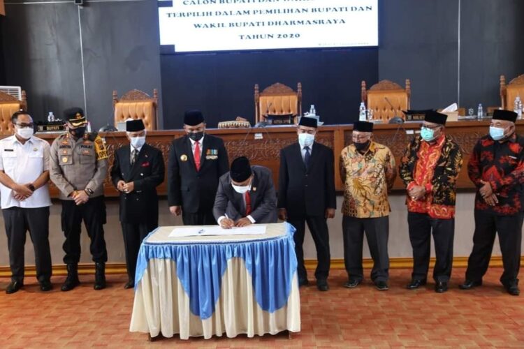 TANDATANGAN—Ketua DPRD Dharmasraya, Paryanto sedang menandatangi hasil paripurna penetapan pasangan Sutan Riska - DP Labuan sebagai Pasangan Calon Bupati terpilih Dharmasraya yang disaksikan langsung oleh Tokoh Masyarakat dan Forkopimda.