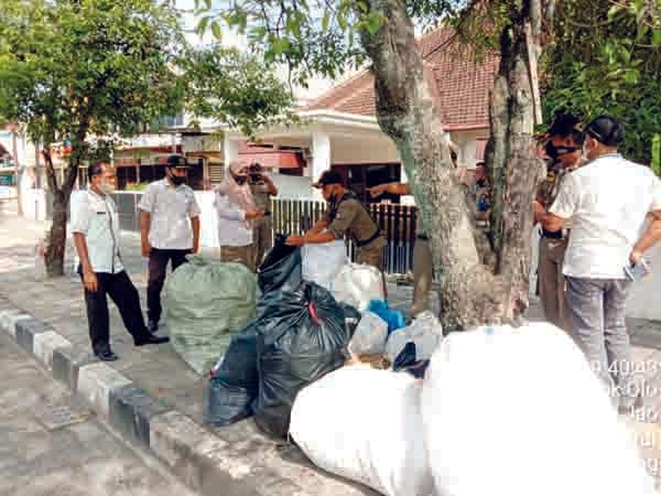 TUMPUKAN SAMPAH— Personel Satpol PP menegur pemulung yang menumpuk barang-barang bekas dan sampah di trotoar di kawasan Kampung Jao, Kecamatan Padang Barat, Jumat (5/2).