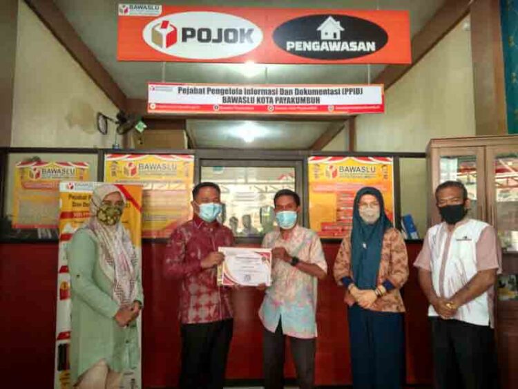 SERAHKAN—Ketua Bawaslu Kota Payakumbuh, Muhammad Khadafi menyerahkan piagam penghargaan kepada Harian Pagi Posmetro Padang.