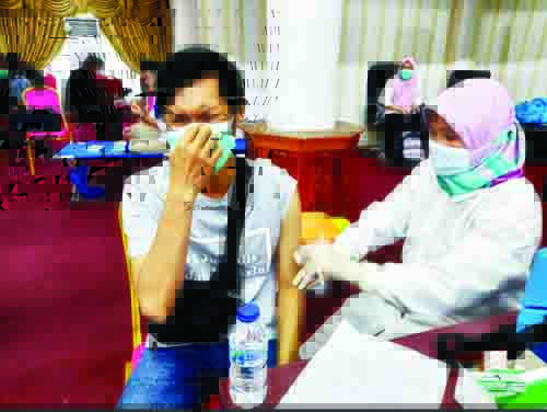 PEJAMKAN MATA— Salah seorang jurnalis media cetak di Kota Padang, memilih memejamkan matanya saat petugas medis mulai menyuntikkan jarum ke lengannya saat vaksinasi missal untuk wartawan di Aula Kantor Gubernur, Rabu (10/3).