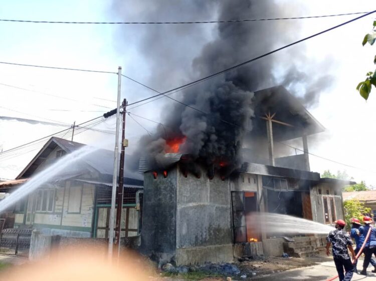 PADAMKAN API—Petugas Damkar melakukan penyemprotan air untuk memadamkan api yang membakar bangunan rumah dan warung penjual gas elpiji dan minyak tanah.