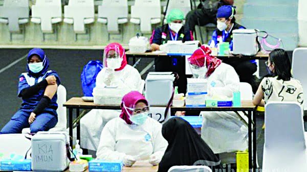 LAYANI—Terlihat petugas vaksin saat melayani warga yang akan disuntik vaksin covid-19.