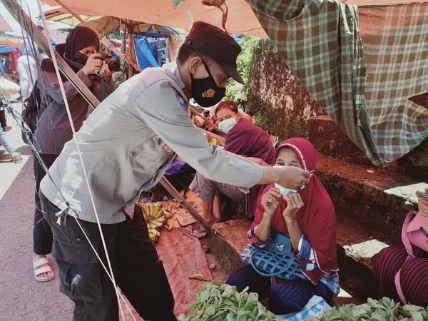 PASANGKAN— Kapolsek VII Koto Sungai Sariak AKP Hepi Kusnadi pasangkan masker kepada salah satu pedagang di Pasar Tandikek.