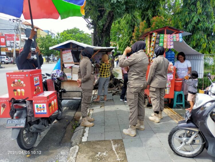 TERTIBKAN PEDAGANG— Petugas Pol PP menertibkan pedagang yang masih berjualan di trotoar.