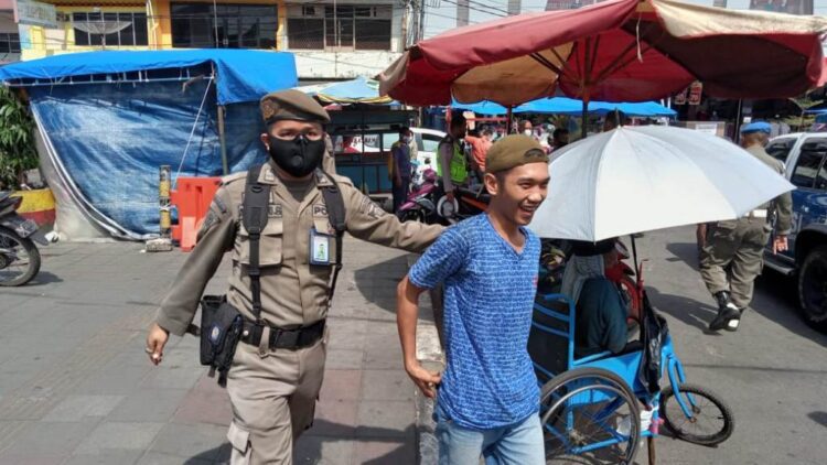 TERJARING OPERASI— Petugas Satpol PP dan tim gabungan merazia sejumlah warga yang tidak pakai masker. Puluhan warga dibawa ke Mapolresta untuk didata.
