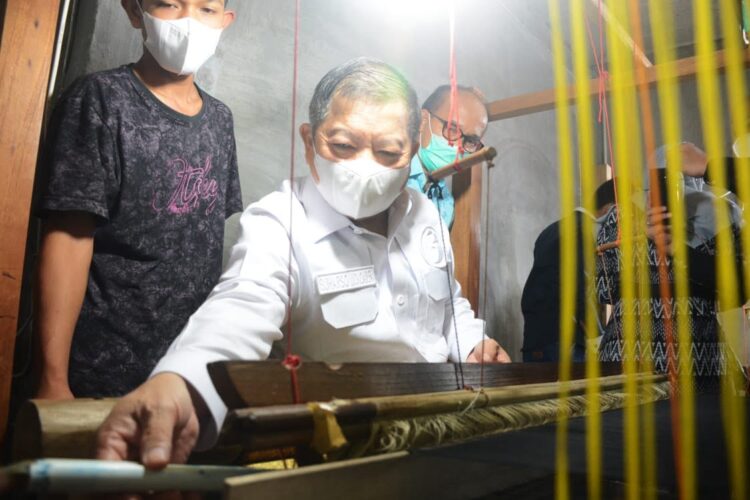 Menteri PPN/Kepala Bappenas Suharso Monoarfa menenun songket.