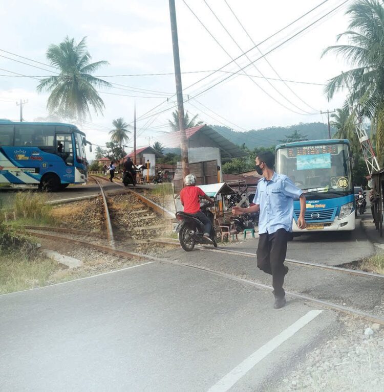 BERLARI MELIHAT KERETA API— Pramugara Trans Padang harus turun dari bus untuk melihat KA, apakah melintas di perlintasan KA Simpang Anak Aia, Rabu (26/5). Kondisi jalan yang sempit dan tidak adanya palang kereta api membuat jalur ini rawan kecelakaan setiap harinya.