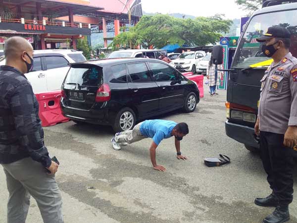 SANKSI PUSH-UP—Kasat Binmas Polres Pessel AKP. Gusfriandi mengawasi seorang pelanggar prokes dengan melakukan push up.