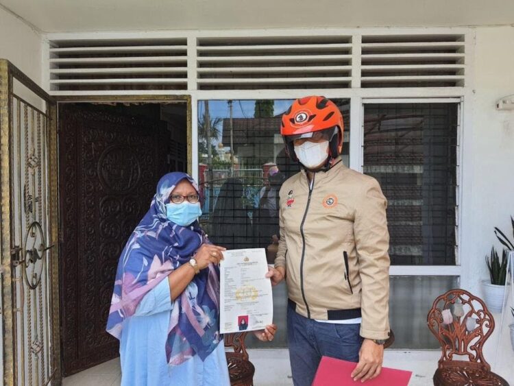 DIANTAR—Seorang anggota Ditintelkam Polda Sumbar dengan senang dan senyum mengantarkan SKCK ke alamat rumah pemohon.