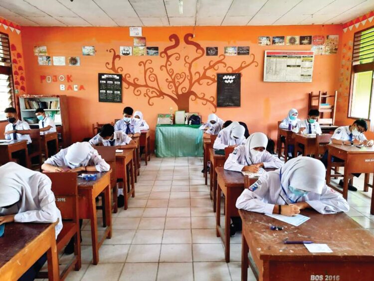 UAS HARI PERTAMA— Dengan menjalankan protokol kesehatan (prokes) ketat, siswa dan siswi SMP Negeri 21 Padang melakukan Ujian Akhir Sekolah (UAS), Senin (24/5). Di hari pertama, ujian berjalan dengan lancar dan tertib.