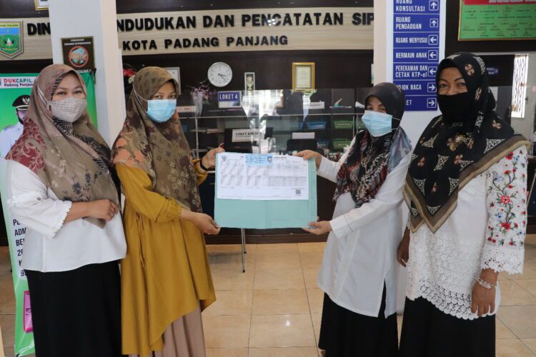 FOTO BERSAMA— Petugas Disdukcapil foto bersama dengan masyarakat yang mengurus Adminduk ke Disdukcapil setelah penyerahan berkas.