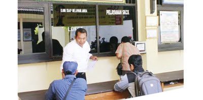 LAYANAN SKCK— Seorang petugas polisi berpakaian preman melayani beberapa orang warga mengurus SKCK di salah satu kantor polisi.