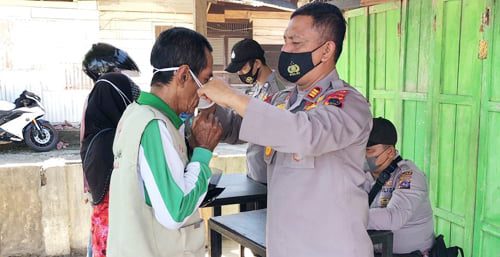 PAKAIKAN—Terlihat Kasat Shabara polres Pasbar AKP Yulandi, sedang memakaikan masker gratis, bagi para pelangar prokes kesehatan saat razia kemarin.