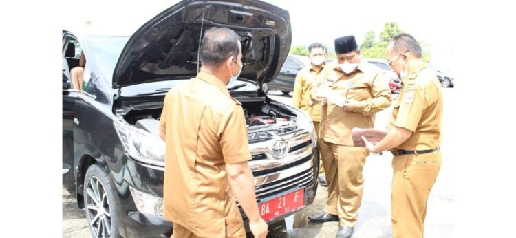 CEK—Suhatri Bur saat mencek STNK dan surat surat mobil dinas serta mesin kendaraan.