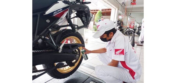 BERIKAN PELUMAS-Mekanik Honda memberikan pelumas pada rantai sepeda motor agar tetap awet.