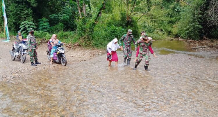 Akses Jalan Rusak, Satgas TMMDN Kodim 0306/50 Kota Bantu Murid SD Seberangi Anak Sungai 1 BANTU SEBERANGI SUNGAI— Personel Satgas TMMD ke-111 Kodim 0306/50 Kota yang sedang membantu warga masyarakat dan anak anak dalam menyeberangi anak sungai dengan kendaraan bermotor, Selasa (13/7).