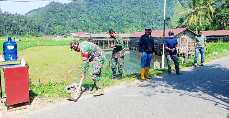 GORO— Anggota Satgas TNI Manunggal Membangun Desa/Nagari (TMMD/N) ke-111 bersama warga melakukan gotong royong di sekitar Posko PPKM Nagari Talang Maur.