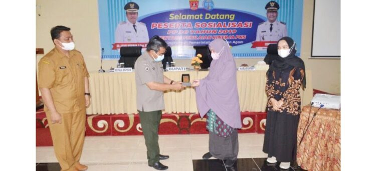 SERAHKAN CENDERA MATA— Sekdakab Agam Martias Wanto menyerahkan cendera mata kepada salah seorang peserta sosialisasi  PP 30 /2019 tentang Penilaian Kinerja PNS.