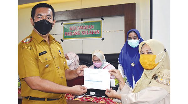 Camat Padang Selatan Teddy Antonius,S.STP, MM menyerahkan kartu vaksinasi Covid-19 kepada peserta vaksinasi, Zurlinda, warga Cendana Mata Air.