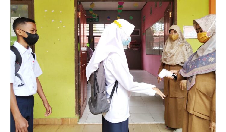 UKUR SUHU— Majelis guru mengukur suhu siswaa yang akan melakukan belajar tatap muka terbatas di sekolah.