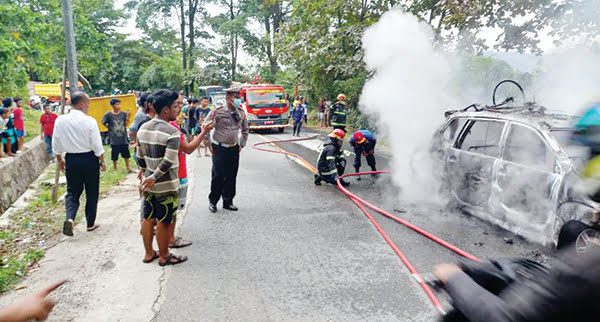 KEBAKARAN— Petugas Damkar melakukan penyemprotan air untuk memadamkan api yang membakar mobil travel.