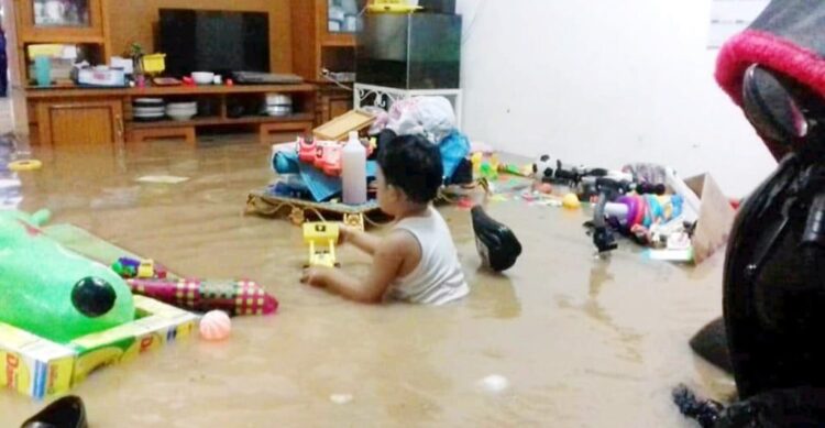 BERMAIN DI TENGAH BANJIR— Seorang anak terlihat tetap asyik bermain meski rumahnya sudah terendam banjir, Rabu (18/8) malam.