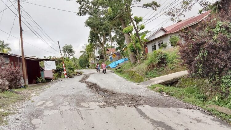 TERBELAH--Kondisi jalan utama yang terbelah di tengahnya, sehingga terjadi parit bila hujan turun, air mengalir deras di tengahnya.