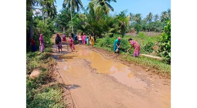 PERBAIKAN JALAN KAMPUNG— Belasan orang emak-emak bahu membahu bergotong royong melakukan perbaikan jalan kampung.
