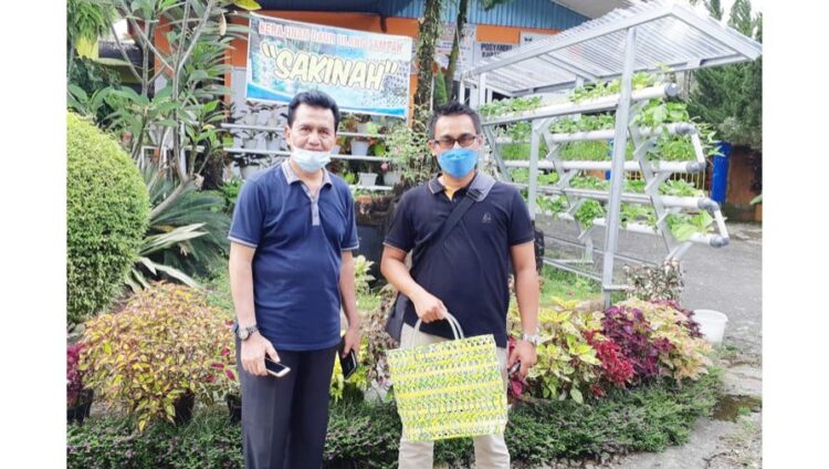 PLN Peduli Berdayakan Bank Sampah Sakinah di Kota Padang 1 Kepala Seksi Kemitraan Dinas Lingkungan Hidup Kota Padang, Elfauzi Bersama Asisten Manager Komunikasi dan TJSL PLN UIP Sumbagteng, Fadhli, dengan tas keranjang salah satu hasil olahan sampah.