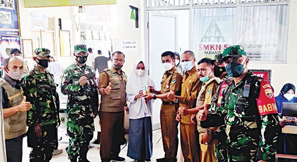 DIKASIH NUTRISI— Kepala Dinas Pendidikan Sumbar Adib Alfikri memberikan nutrisi makanan berupa roti dan susu kotak kepada seorang siswi saat melakukan vaksinasi massal di SMKN 5 Padang.