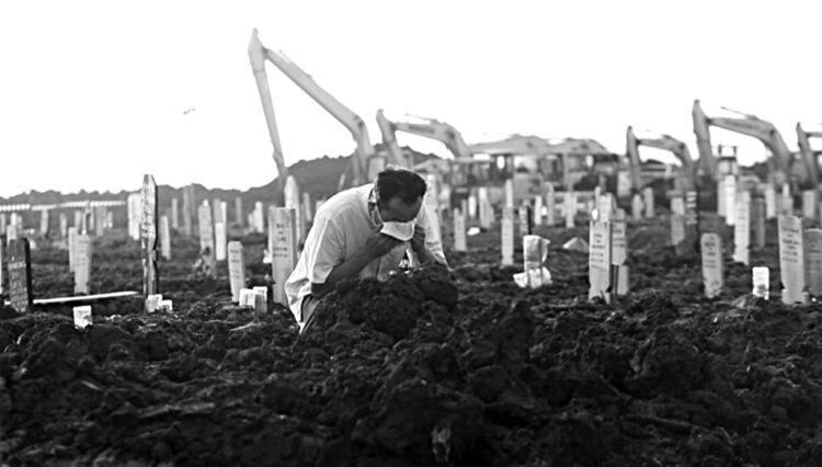 SAKSIKAN PEMAKAMAN— Warga saat menyaksikan pemakaman keluarganya dengan protokol Covid-19.