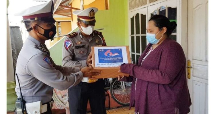 SERAHKAN BANTUAN— Terlihat dua personel Satlantas Polres Padangpariaman serahkan langsung  bantuan sosial ke tangan warga.