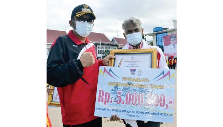 SERAHKAN PENGHARGAAN— Wali Kota Padang Hendri Septa menyerahkan penghargaan wartawan olahraga terbaik, Adril Mahaputra, saat Upacara Peringatan Haornas ke-38 tingkat Kota Padang tdi Lapangan Upacara Komplek Perkantoran Balai Kota Padang, Kamis (9/9) pagi.