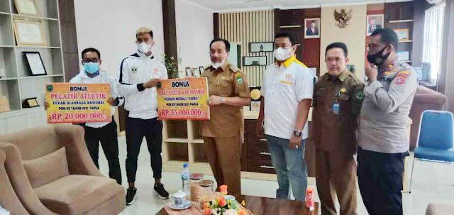 SERAHKAN BONUS—Bupati Pasaman Benny Utama didampingi Ketua KONI Pasaman Tommy Irawan saat menyerahkan bonus sebagai penghargaan kepada Fauma Defril Jumra dan pelatih.