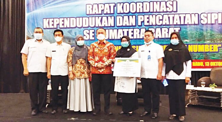 Sekdakab Pasbar Hendra Putra dan Kadisdukcapil Hj Yulisna foto bersama sambil memegang penghargaan Adminduk 2021.