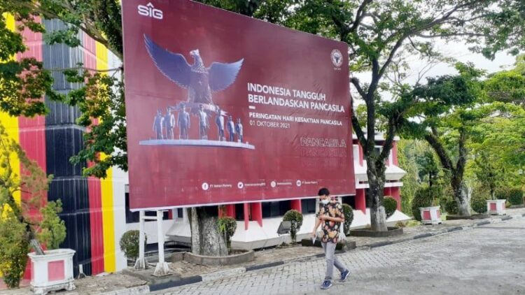PERINGATI HARI KESAKTIAN PANCASILA— Seorang pria berjalan di depan Baliho peringatan Hari Kesaktian Pancasila yang dipasang di Plaza Kantor Pusat PT Semen Padang, Jumat (1/10). Manajemen PT Semen Padang mengajak seluruh karyawan Semen Padang Group untuk mengibarkan bendera setengah tiang pada tanggal 30 September dan bendera satu tiang pada 1 Oktober 2021.