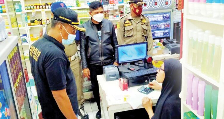 ABAI PROKES— Petugas Satpol PP Kota Padang melakukan pengawasan di sejumlah Swalayan di kawasan Lubeg, Jumat (12/11) malam. Masih banyak pengunjung dan juga kasir Swalayan yang tidak memakai masker.