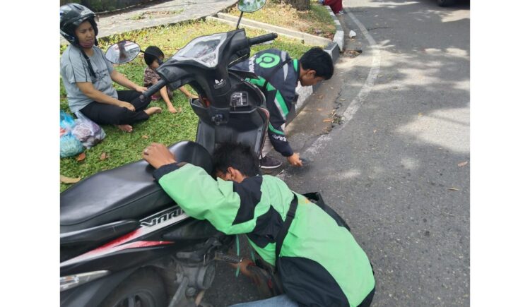 AKSI SOSIAL—Terlihat aksi sosial dua pengendara Gojek menolong IRT Elmi yang duduk bersama balitanya.