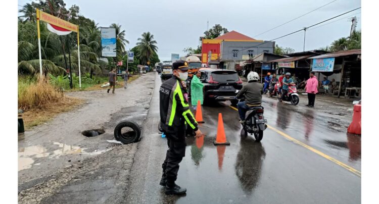 ATUR LALIN—Anggota Satlantas Polres Padangpriaman mengatur arus lalu lintas akibat amblasnya jalan lintas Padang menuju Bukittinggi di Kasai, Kecamatan Batang Anai.