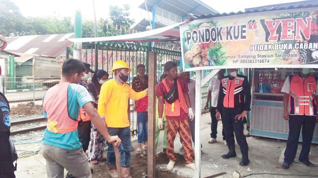 PEMASANGAN PAGAR — Petugas dari PT KAI Divre Ii Sumbar sedang melakukan pemasangan pagar di depan akses masuk kios di Pasar Tarandam, Kamis (25/11).