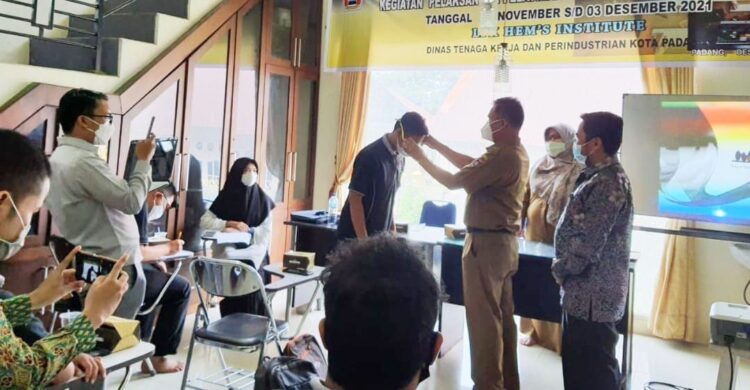PASANGKAN TANDA PESERTA —Kadis Nakerin Padang Endrizal memasangkam id card kepada salah seorang peserta.