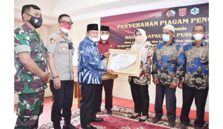 PENGHARGAAN— Bupati Agam Dr. H. Andri Warman bersama Kapolres Bukittinggi, AKBP Dody Prawiranegara dan perwakilan Dandim 0304 Agam, menyerahkan penghargaan kepada Puskesmas Kapau dan NAgari Kapau, Kamis (25/11).
