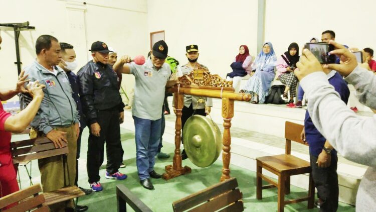 PUKUL GONG PEMBUKA— Ketua DPRD Padang Syafrial Kani yang didampingi Anggota DPRD Padang Manufer Putra Firdaus, Kadispora Padang Mursalim serta Ketua KONI Padang Yusra Syarif  secara resmi membuka pertandingan cabor MMA di ajang Porkota 2021 di GOR Beladiri GOR H. Agus Salim, Sabtu (18/12).