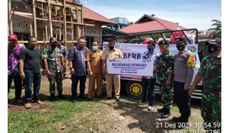 SERAHKAN SEMBAKO— Jajaran manajemen BRI foto bersama usai serahkan sembako kepada warga yang terdampak banjir.