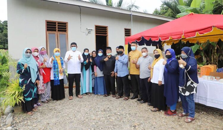 FOTO BERSAMA— Pengurus BKMT Kelurahan Gunung Pangilun, Wako Hendri Septa berfoto bersama di depan rumah yang dibangun untuk Khusmida (54) dan dua anaknya, di Jalan Swadaya RT 03 RW 07.