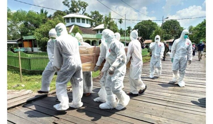 PAKAI APD— Petugas dengan APD lengkap membawa jenazah dengan protokol Covid-19.
