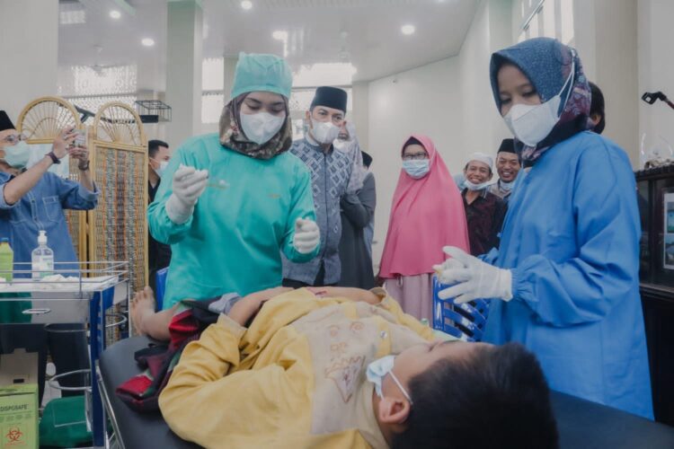 KHITAN MASSAL—Wako Sawahlunto Deri Astra menyaksikan seorang anak saat dikhitan di Masjid Al- Mujahidin, Desa Kolok Mudiak Kecamatan Barangin.