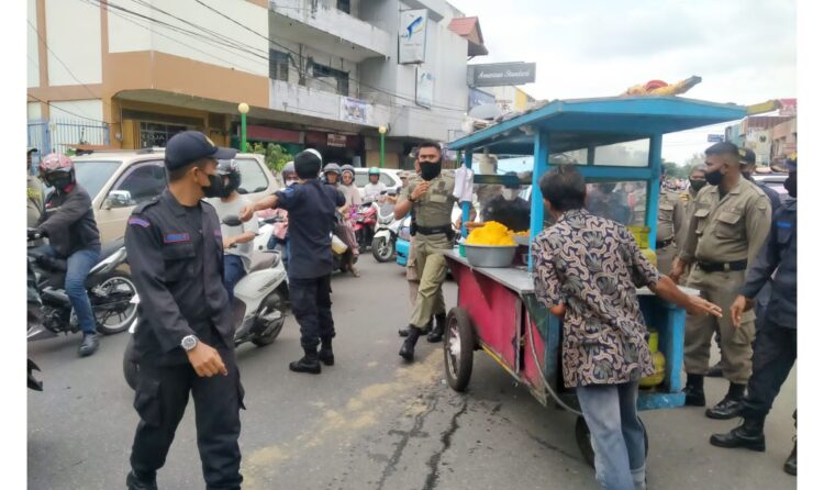 PEMINDAHAN GEROBAK— Petugas gabungan Satpol PP Padang membawa gerobak milik PKL yang berjualan di bundaran air mancur, Selasa (1/2). Dalam penertiban ini, petugas Satpol PP diserang pedagang dengan minyak panas, karena menolak
 lapak atau gerobaknya dipindahkan.
