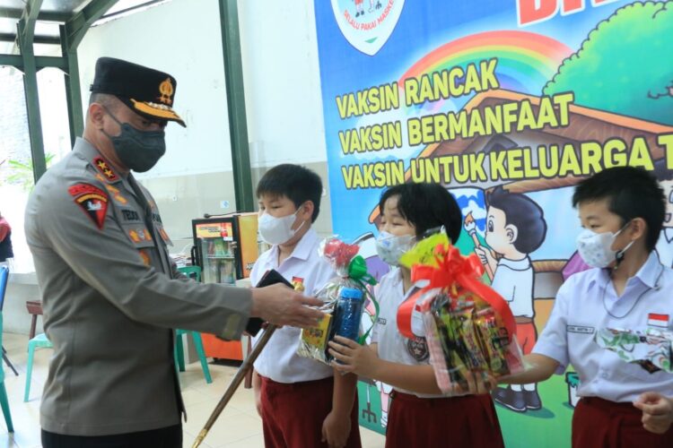BERIKAN BINGKISAN—Kapolda Sumbar Irjen Pol Teddy Minahasa memberikan bingkisan kepada siswa-siswi SD Agnes Padang yang divaksin.